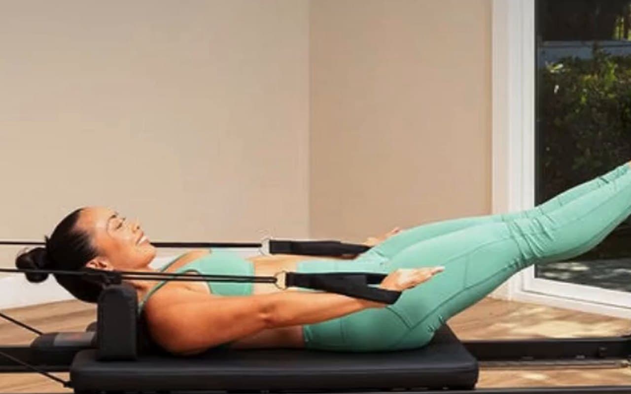 Woman exercising on a Sunny foldable Pilates reformer at home